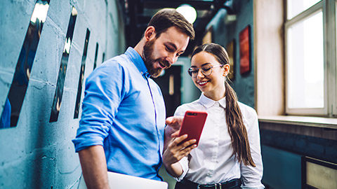 Colleagues in hallway looking at screen of phone