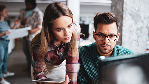 Coworkers looking at computer screen with concerned looks on their faces