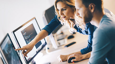 Colleagues pointing at computer screen that is full of computer code