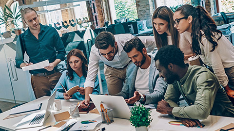 Group crowded around a computer watching something being demostrated on the screen