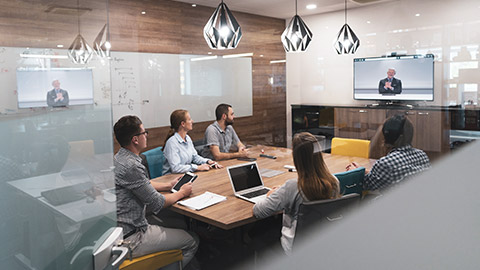 Business group sitting around a boardroom table watching online presentation