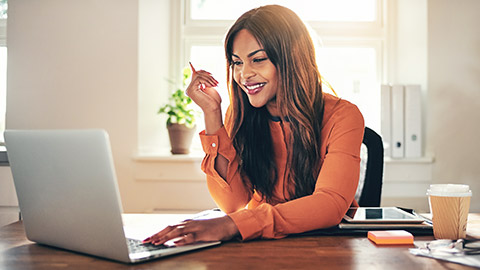 A smiling female accountant sitting at a desk while looking at her laptop computer