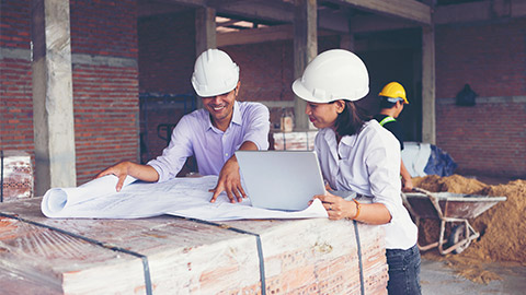 Two people looking over reports and plans on a construction site