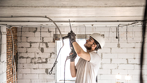 An electrician removing existing services from a structure on site