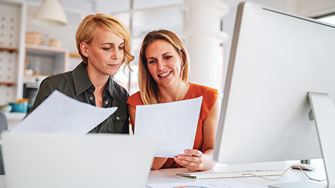 2 female coworkers discussing accounting numbers while sitting at a desk