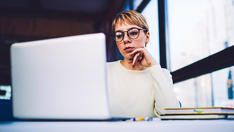 Young female designer sitting at desk concentrating on her laptop